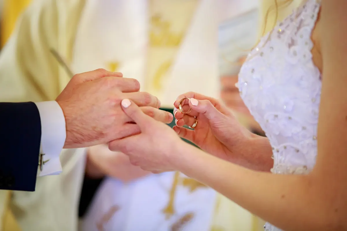 Zakładanie obrączki podczas ceremonii ślubnej, zbliżenie na dłonie