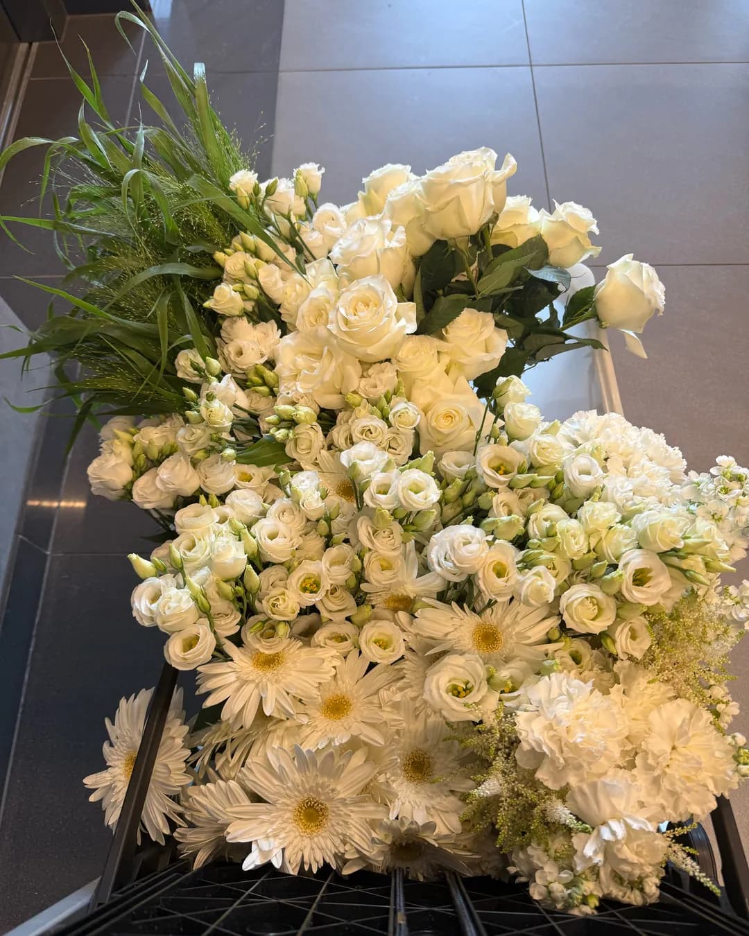 White roses, eustomas, gerberas, carnations and ornamental grasses arranged on a black box, ready for decoration assembly