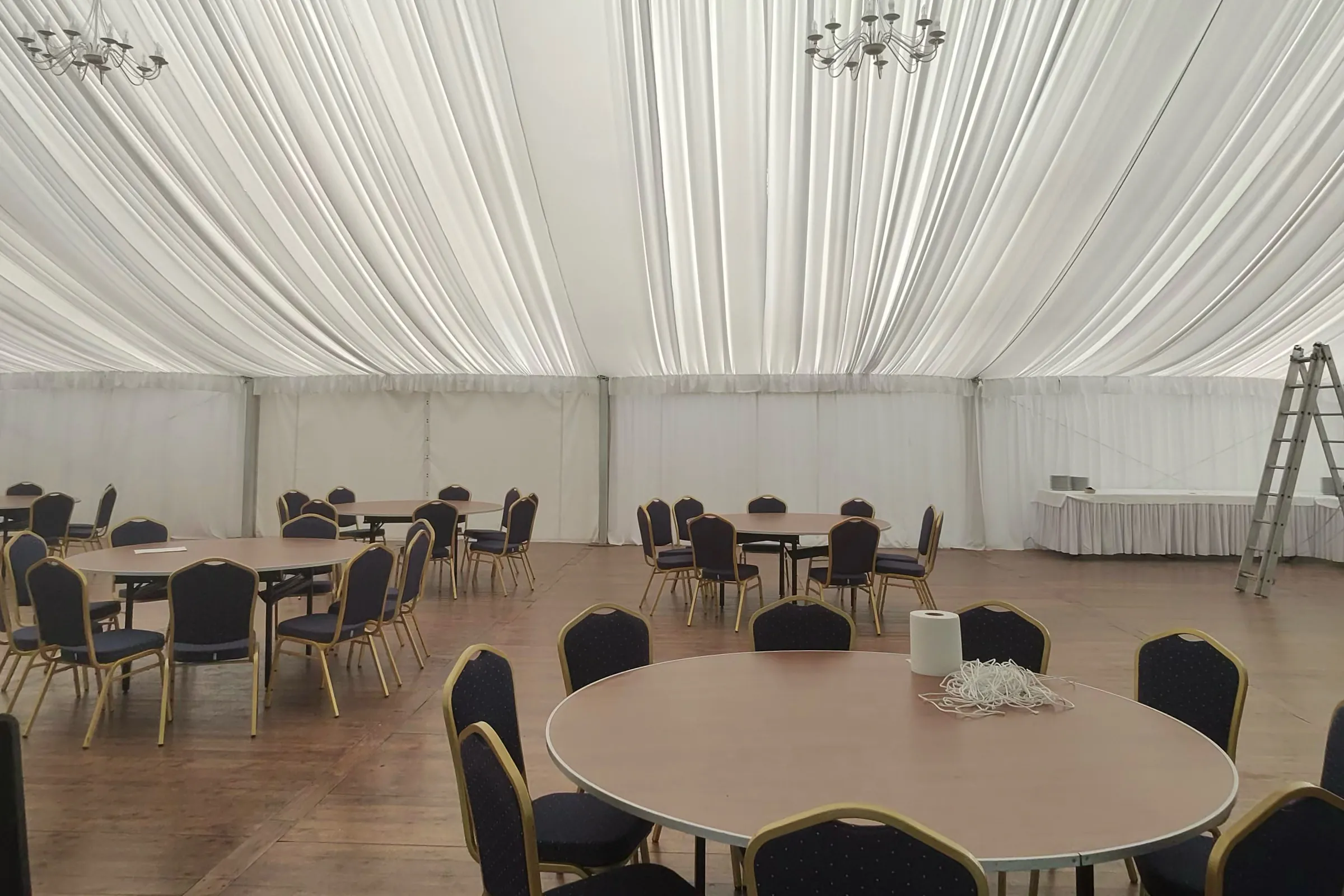 The pavilion before decoration: the fabric from the ceiling is already hung, the tables are still without tablecloths, the chairs are without covers.