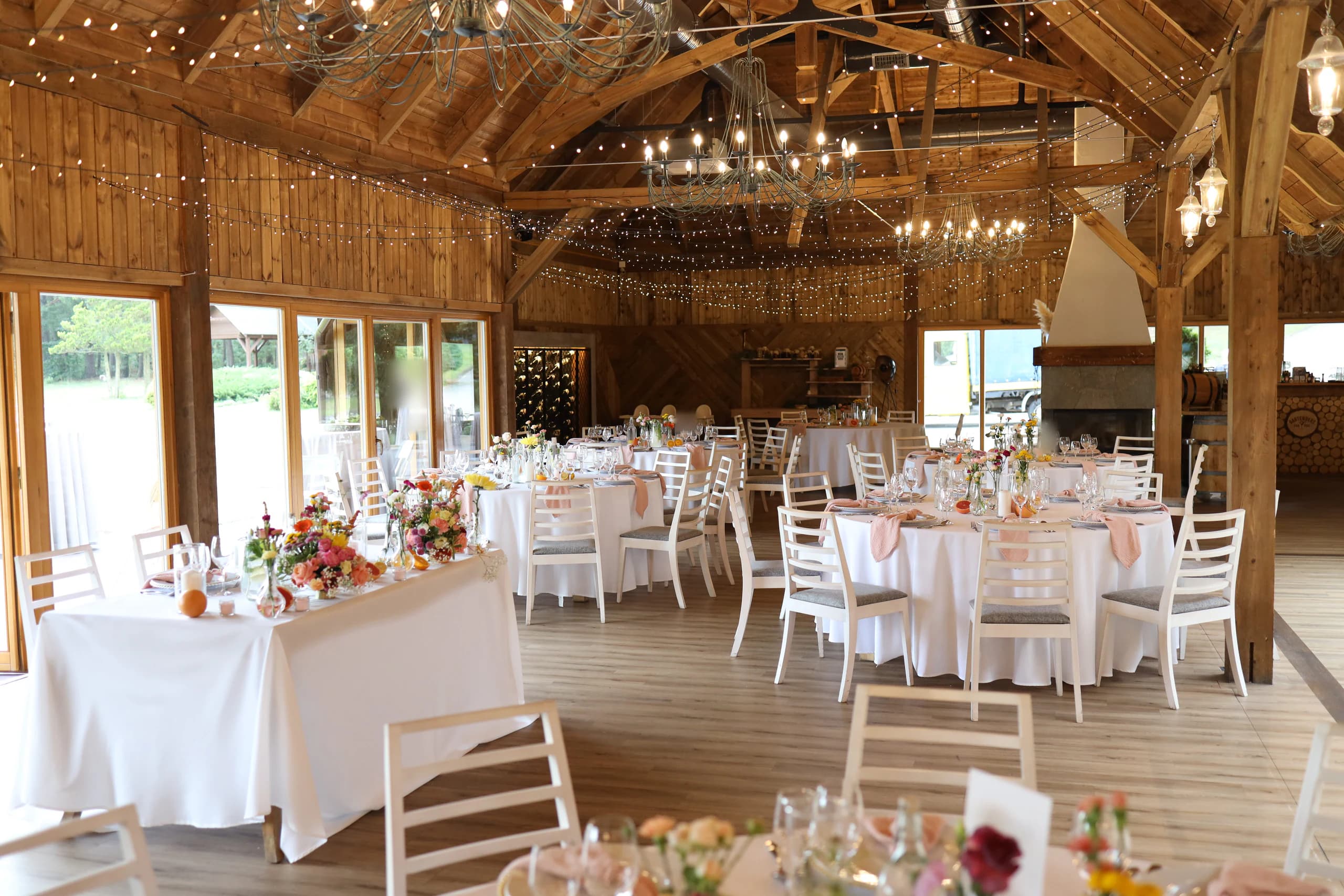 The room on the other side: on the left, a rectangular table with lush compositions next to the glass wall, then round tables, in the background there is a fireplace