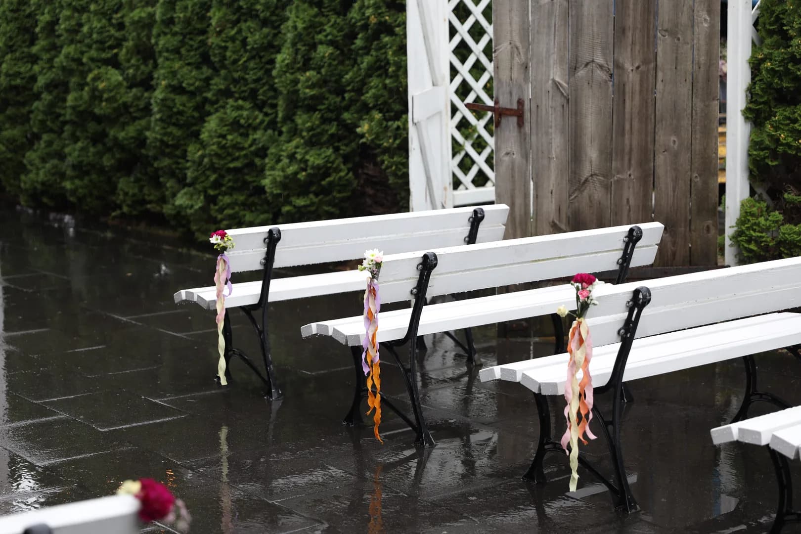 White benches with black legs and bouquets of chrysanthemums and carnations with long colorful ribbons